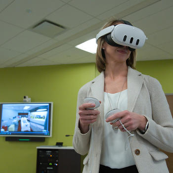 Vice President of Operations Heather Causseaux experiences a virtual reality nursing simulation in George Mason's Lab for Immersive Technologies and Simulation